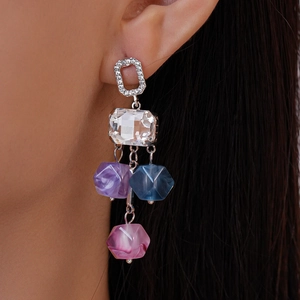 Gros plan de boucles d'oreilles géométriques en argent avec cristaux colorés sur un mannequin