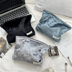 Detailed flat lay of velvet makeup bags in black, gray-blue, and silver with soft texture
