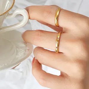 Detailed view of a gold-plated ring with red, green, and clear stones on a hand