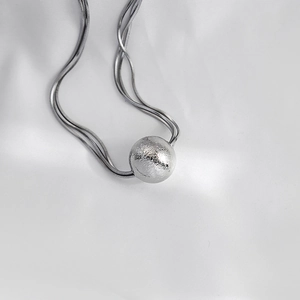 Detailed close-up of double-layer snake chain necklace with a matte finish metal ball pendant