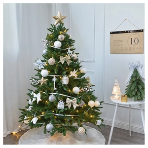 Close-up of golden Christmas ornaments and glowing LED lights on a lush green tree branch