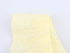 Close-up of pale yellow bubble crepe fabric texture for women's summer dresses