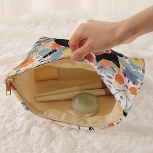Floral corduroy makeup bag with book and cat print featuring a gold zipper closure