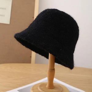 Gros plan détaillé d'un chapeau bob en fausse fourrure noire sur un support en bois