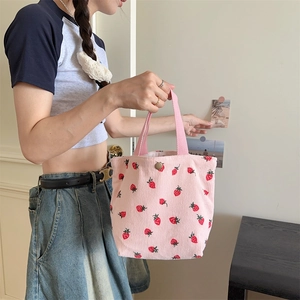 Détail du sac fourre-tout en velours rose avec imprimé fraise et bouton pression