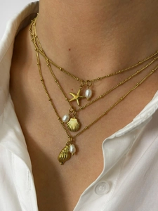 Detailed view of triple-layered gold ocean necklaces with starfish and shell charms