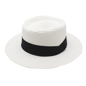 Détail du tissage d'un chapeau de paille beige à large bord avec ruban noir chic