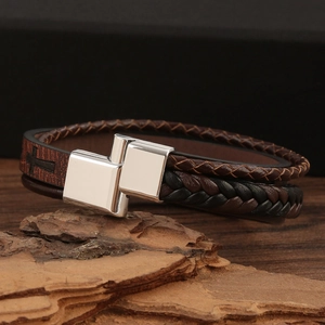 Detail of retro braided leather bracelet on wood bark with polished steel clasp
