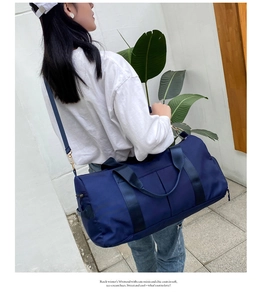 Blue nylon travel bag with shoulder strap shown carried by a model outdoors