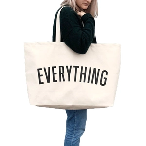 Close-up of oversized cream canvas tote bag with bold black EVERYTHING printed text