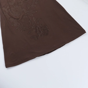 Detailed macro view of the rhinestone flower pattern on the brown mini dress hemline