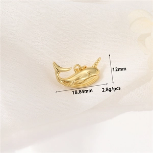 Macro view of a 14K gold narwhal pendant on white fabric with size and weight details