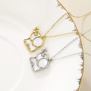 Close-up of gold and silver elephant pendants with shell inlay on white ceramic tray