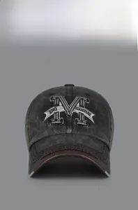 Detailed view of 3D M letter embroidery and brown leather trim on vintage washed grey baseball cap