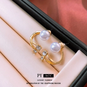 Golden C-shaped earrings with double pearls and crystals in a luxury jewelry box