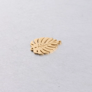 Macro detail of golden stainless steel monstera leaf pendant with double connector holes