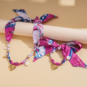 Detailed view of pink floral fabric choker with gold heart and smile flower charms