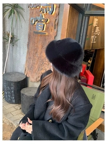 Chic black faux fur bucket hat shown in outdoor street style for winter warmth