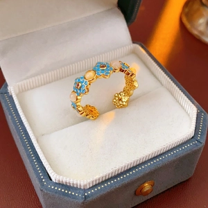 Macro shot of 18k gold plated flower ring with blue enamel and pink gemstone detail