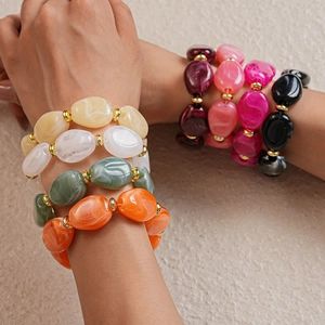Detail of chunky acrylic link bracelets featuring marble textures and gold metal spacers