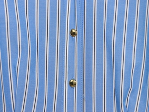 Detailed close-up of blue and white striped fabric with premium gold metal buttons