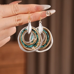 Close-up of layered round earrings with turquoise texture and silver leaf accent