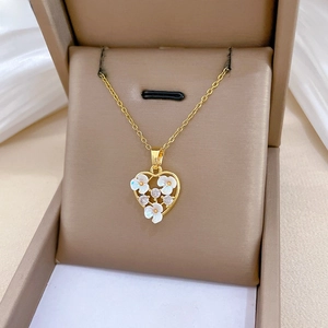 Close-up of golden heart pendant featuring shell flower petals and sparkling zircon stones