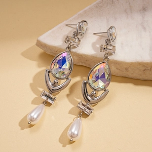 Detail of silver drop earrings with iridescent crystals and pearls on a stone base