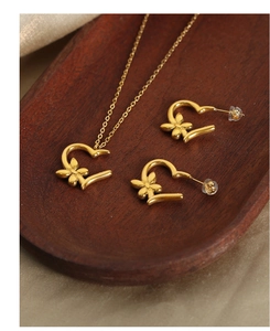 Macro shot of gold heart-shaped flower jewelry set on wood and beige silk