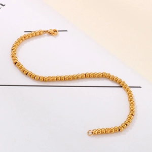Polished golden stainless steel 4mm bead bracelet with lobster clasp on elegant background