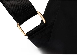 Close-up of golden metal buckle and high-density black nylon fabric texture on travel backpack