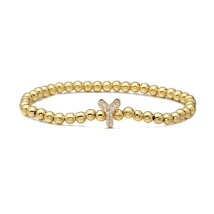 Detailed macro of golden beaded bracelet featuring a pavé encrusted letter Y charm