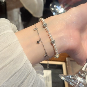 Detail of layered pearl bracelet with zircon star charms on a woman's wrist