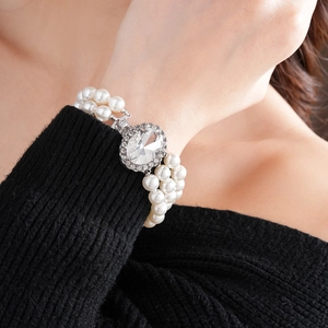 Primo piano di un bracciale di perle multistrato con un grande cristallo ovale al polso