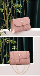 Detailed view of pink quilted handbag featuring pearl cat ornament and gold fringe tassel