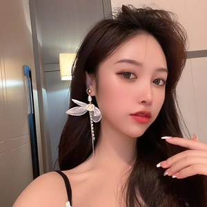 Close-up of elegant lace bow earrings with pearls and long gold metal chains