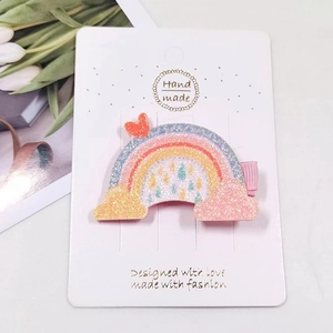 Close-up of glittery rainbow hair clip with heart detail on a white display card