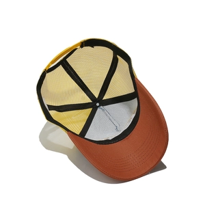 Detail view of yellow mesh trucker hat with snapback closure and maroon visor