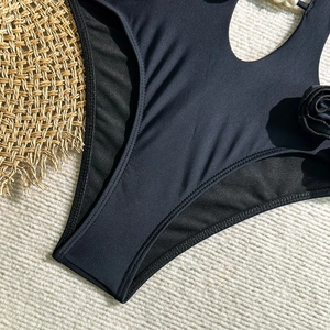Detail of black swimwear featuring a 3D rose ornament with a pearl on ribbed fabric