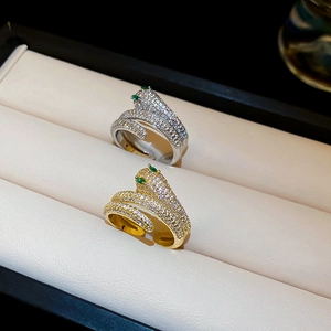 Macro detail of gold and silver snake rings with white cubic zirconia and green gem eyes