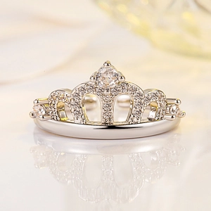 Sparkling silver crown ring with brilliant cubic zirconia stones on reflective surface