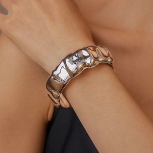 Macro shot of silver textured wide cuff bracelet with flowing lava-like ripple patterns