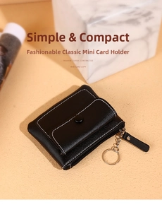 Macro detail of slim black card wallet with white stitching and metal keychain