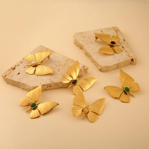 Artistic detail of gold dragonfly earrings with natural stones and pearl accents