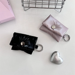 Detail of quilted puffer headphone cases in black and lilac with metal snap closure