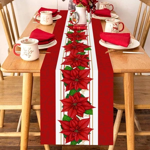 Christmas table runner featuring red poinsettia flowers on a rustic wooden dining table