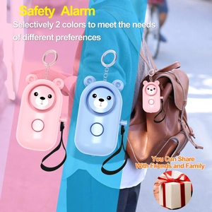 Detail of bear-shaped personal safety alarm on a leather bag with pink and blue variants