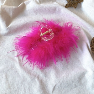 Detail shot of a pink ostrich feather hair claw clip with golden spring and fluffy texture