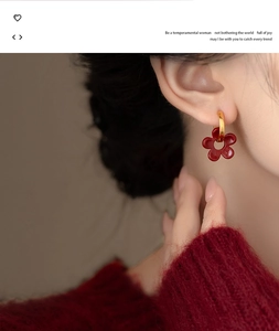 Gros plan d'une femme portant des boucles d'oreilles fleur rouge vintage émaillée