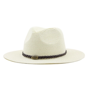 Detail of cream straw fedora hat featuring a brown leather band and bull metal emblem
